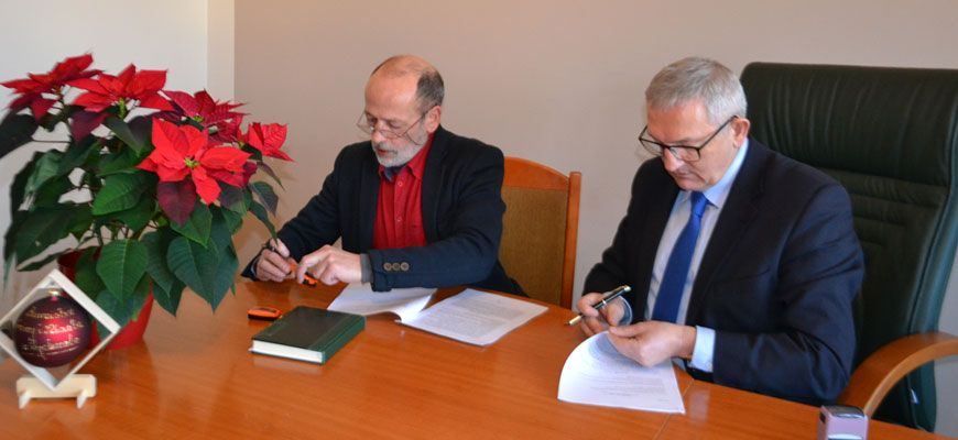 Zmiany w gospodarce odpadami_1: Zdjęcie przedstawia dwóch panów siedzących przy biurku z długopisami w dłoniach.