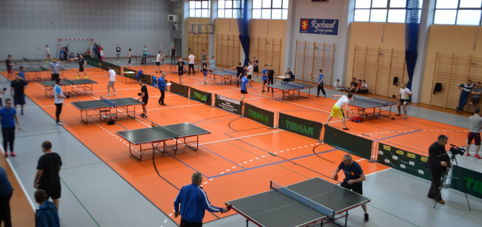 IV Gminny Turniej Tenisa Stołowego_10 zdjęcie przedstawia: salę gimnastyczną i stoły do tenisa stołowego oraz ludzi grających