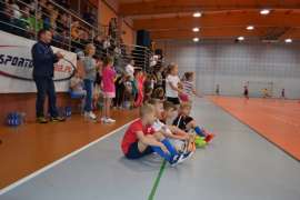 Olimpiada: Zdjecie przedstawia siedzące dzieci na podłodze hali sportowej