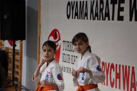 Mistrzostwa Oyama Karate w Kata_3 zdjęcie przedstawia: dwie dziewczynki, zawodniczki w białych strojach na tle napisu