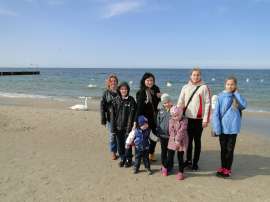 Turnus rehabilitacyjny 2016_4 zdjęcie przedstawia: pięcioro dzieci wraz z opiekunami na plaży, w tle morze