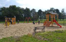 Place zabaw_5: Zdjęcia przedstawia drewniane huśtawki, ślizgawki i drabinki stojące na piasku