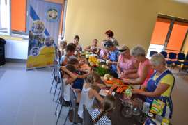 UTW Rychwał: zdjęcie przedstawia kobiety i dzieci obierające warzywa