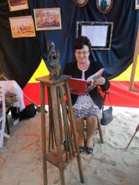 Wilczyn Ruszenie Powiatu: Zdjęcie przedstawia Elżbietę Streker-Dęmbińska siedząca na krześle i czytającą książkę.