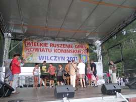 Wilczyn Ruszenie Powiatu: Zdjęcie przedstawia moment wręczania medali uczestnikom imprezy na scenie.