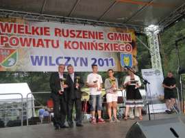 Wilczyn Ruszenie Powiatu: Zdjęcie przedstawia nagrodzonych pucharami uczestników imprezy na scenie.